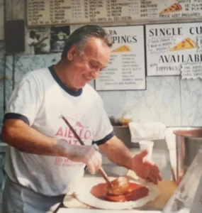 Joe adding sauce to pizza dough